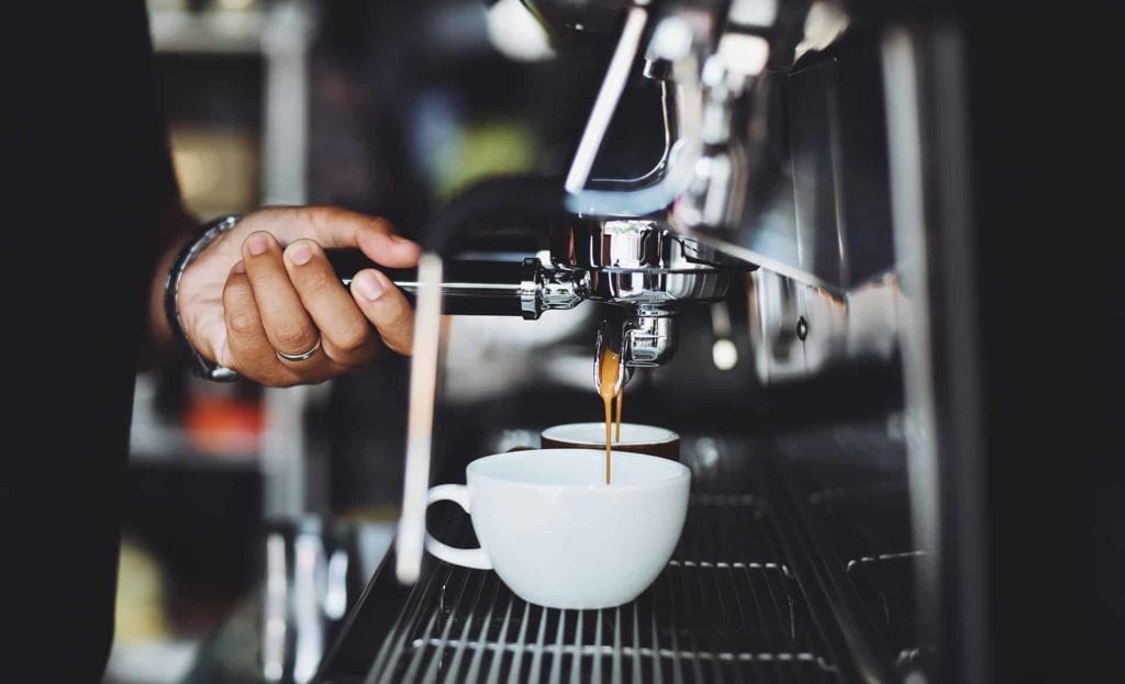 Close up of a coffee cup in a coffee machine being made by a barista